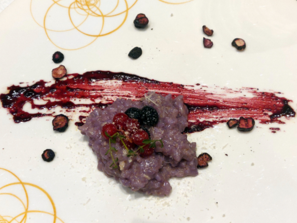 Blue pea tea risotto with blueberry compote, fresh berries soaked in grape seed oil and robiola cheese